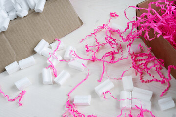 Two cardboard open boxes with pink Crinkle Cut Paper Shred Filler and foam filler for safe packaging and shipping.