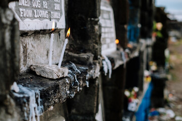 Lighted candle placed in front of the apartment tomb upon a visit to a dead family member's grave. Selective focus. Copy space.