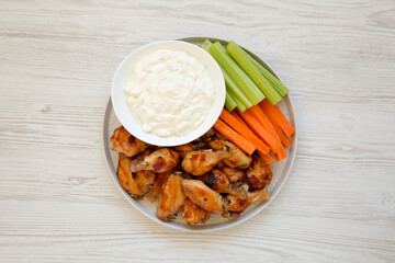 Homemade Chicken Wings with Blue Cheese Dip on a white wooden background, top view. Flat lay, overhead, from above.