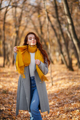 Portrait of young woman walking outdoors in autumn park