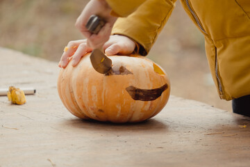 Preparation for Halloween: girl cutting pumpkin. Closeup. Holiday decoration concept. Woman...