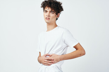 curly guy in a white t-shirt holding his stomach diarrhea discomfort