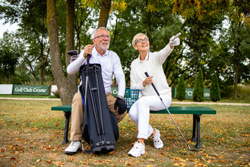 Portrait of smiling senior couple on golf course enjoy watching the game tournament.