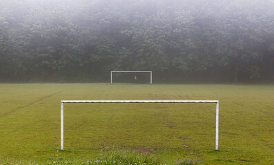 The girl or women runs on the field between the goals in the grass in the fog and rain in the park. Horizontal header banner copy space blog background