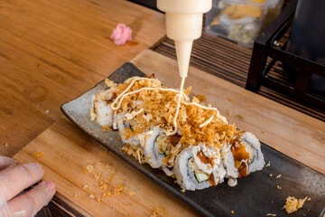 Adding Japanese Mayonnaise on top of a layer of Tenkasu crumbs. Making Tempura Maki rolls.