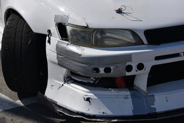 car after the accident. cracked headlight without turn signal. Broken bumper repaired with gray tape