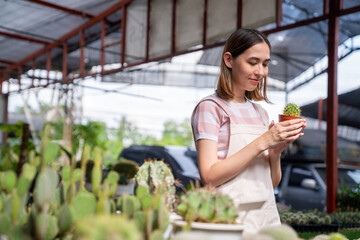 Asian woman gardener working houseplant and flowers in greenhouse garden. Female florist plant shop owner caring and checking plants in store. Small business entrepreneur and plant caring concept.