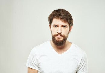 Fototapeta premium bearded man in a white t-shirt irritated facial expression light background