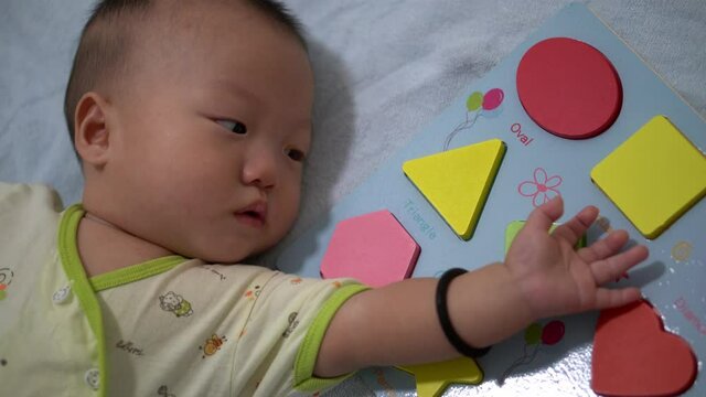 Baby sleep beside shape block sorting toy. Early preschool education concept