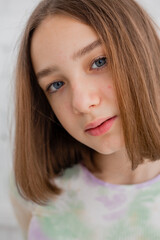 Naklejka premium portrait of a slender teenage girl in a light turtleneck in natural light against a white brick wall. natural beauty, no makeup. problematic skin. space for text. High quality photo