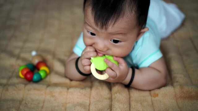 Asian toddler bite the teether at bed