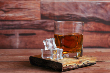 glass of whiskey or cognac on planks with ice cubes