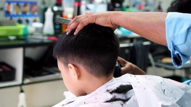 Child cut hair at barbershop. Barber wear face mask