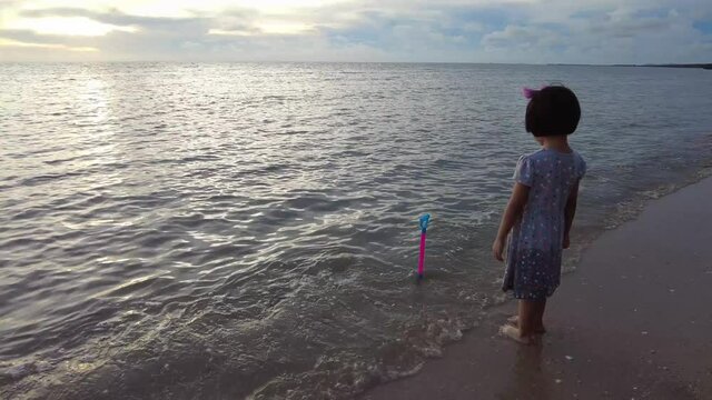 Little girl put shovel beach tool at sea. Summer outdoor activity