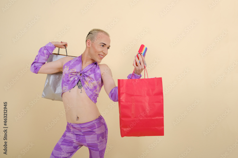 Wall mural Stylish young non-binary person posing to mobile phone camera while taking a selfie with shopping bags.