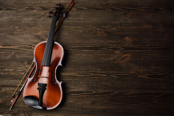 Violin with bow on brown wooden table.