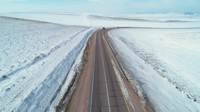 Aerial shot of an intercity road with traffic among the fields covered with snow. Winter landscape