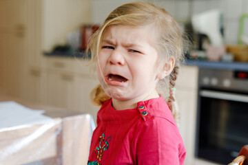 Cute upset unhappy toddler girl crying. Angry emotional child shouting. Portrait of kid with tears.