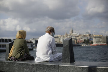 A tour on the coast of the Bosphorus in Istanbul - Turkey Boats and tourists on the Galata Bridge and Galata Tower and fishermen. Seagulls are flying, an old man and his wife are back watching the sun