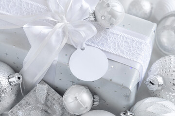 Christmas present with blank gift tag and white decorations, Mockup