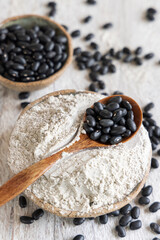 Ceramic bowls with black beans flour with a wooden spoon