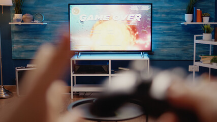 Close up of TV used for gaming concept at home. Video games on television console playing with wireless controller for fun activity. POV of hands holding joystick for digital simulator © DC Studio