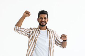 I won. Happy young Indian man gesturing and smiling while standing against white background