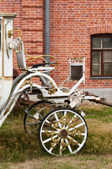 Old white carriage on the background of a red brick building - 463220928