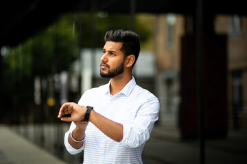 Handsome indian businessman checking time on his watch - obrazy, fototapety, plakaty
