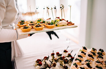 woman hands of a waiter prepare food for a buffet table in a restaurant