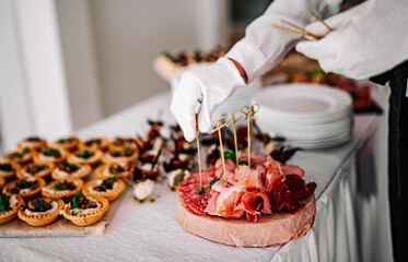 woman hands of a waiter prepare food for a buffet table in a restaurant