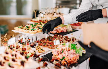 woman hands of a waiter prepare food for a buffet table in a restaurant