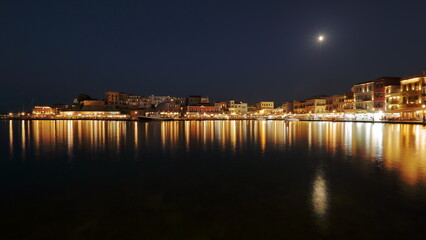 Fototapeta na wymiar Night skyline cityscape of Chania in Crete, Greece, starry sky, full moon, reflections in sea water