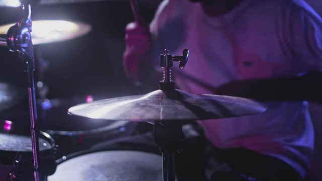 Male Artist hits snare drum, drum kit. Night show in a musical instrument recording studio. The drummer knocks the cymbal crash and hi-hat, Repetition of rock or metal music band, party. Slow motion