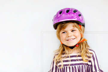 Portrait of happy smiling preschool girl with bycicle helmet on head. Cute toddler child. Safe bike driving with children concept. Safety helmet for kids