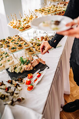 man hands take a snack and put it on plate. buffet in a restaurant