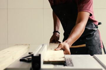 Male carpenter using table saw for cutting a wood