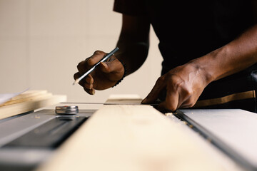 Hand of a carpenter taking measurement of a wooden plank