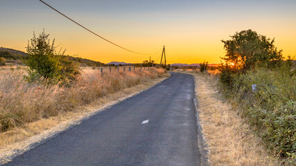 Fototapeta na wymiar Sunrise over road in Causse Blandas