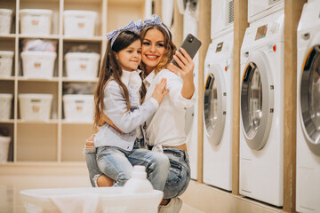 Mother with daughter doing laundry at self serviece laundrette