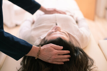 Therapist man doing Holistic therapy Reiki to a woman. Energy treatment with the heat of the palm hands. Japanese energy healing. Wellness, health, relax, well-being and alternative medicine concept. - obrazy, fototapety, plakaty