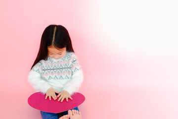 Portrait beautiful cute asian child girl on pink background with red heart sign, valentine day in love concept