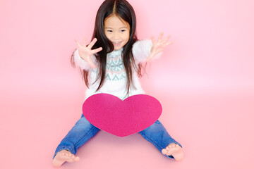 Portrait beautiful cute asian child girl on pink background with red heart sign, valentine day in love concept