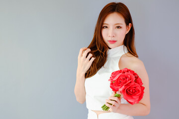 Portrait beautiful asian woman on gray background with red flower bouquet holding in hand, happy valentine day in love concept