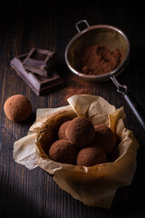 Tasty dark chocolate truffles with cocoa dusting on a brown background
