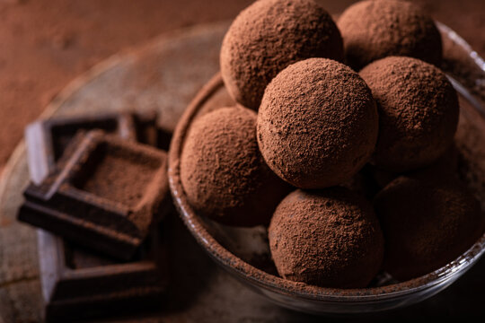 Tasty dark chocolate truffles with cocoa dusting on a brown background
