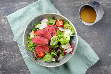 Modern style traditionell gebratene dry aged Bison Rump Steak Scheiben mit Gemüse, Salat und Parmesan Käse serviert als Draufsicht auf einem Nordic Design Schale mit Textfreiraum  