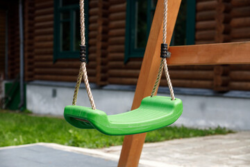 Green plastic swing on ropes in the yard.
