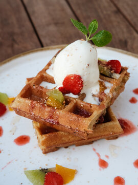 Belgium waffles with fruits and ice cream. Served with plate on wooden table. Selective focus image and close up.
