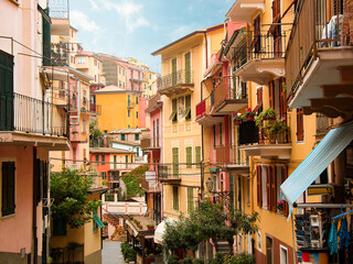 Fototapeta na wymiar Charming colourful houses overlook the street and alley in Manarola a picturesque village in the Cinque Terre, Italy. This famous UNESCO site is popular with tourists